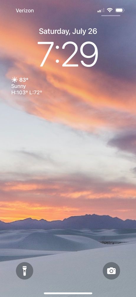 A Lock Screen showing sunset over the white sands national park in colors of grey, dark grey, orange, and dark purple-grey. 