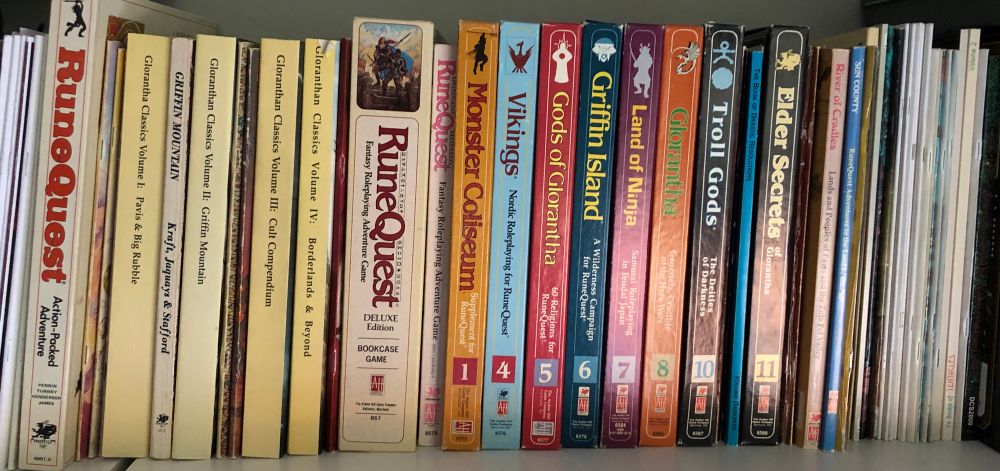 A shelf full of books and boxed sets from the RuneQuest Roleplaying game series.