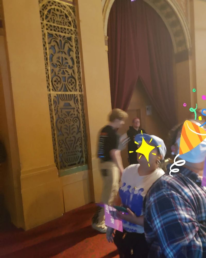 A very blurry photo of Onew from SHINee at The Fillmore in Detroit, walking past the photographer's seat. He is wearing a black concert shirt and khaki colored pants. Please forgive the quality of the photo, for the photographer was too stunned by Onew's presence to get her camera opened in time.