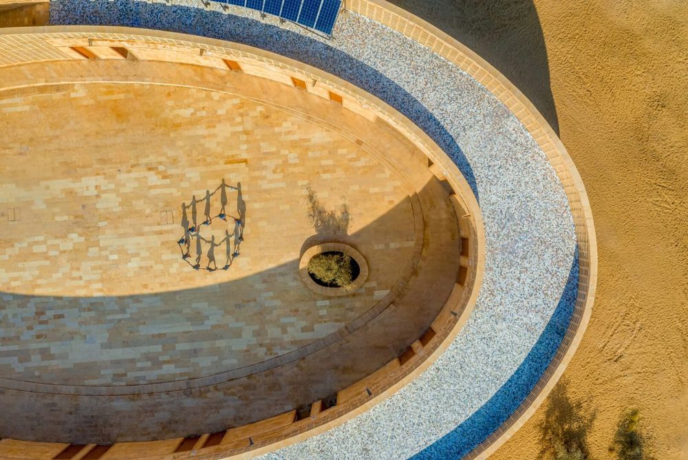 Drone image of a section of the oval building with blue tile on the roof