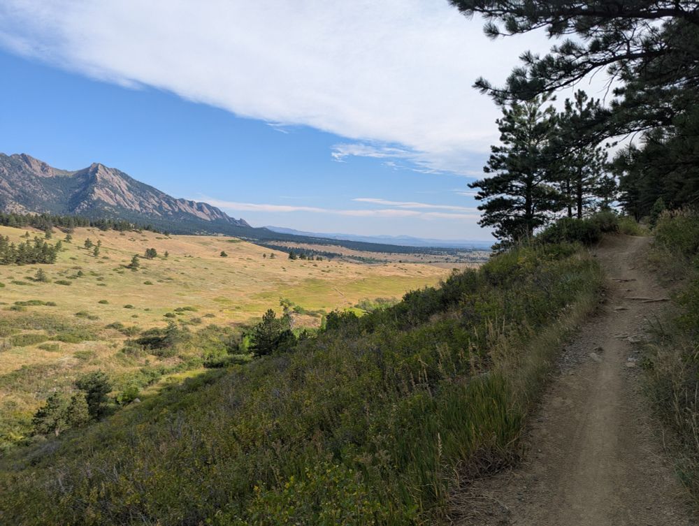 Picture facing the valley with the Boulder Flatirons to the left and trail to the right.