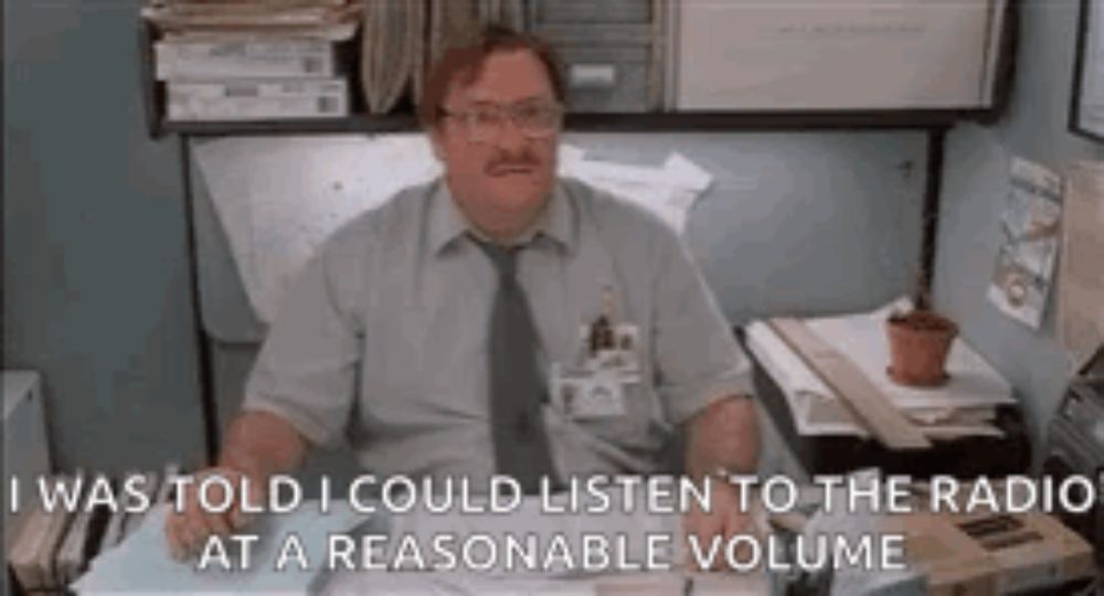 a man is sitting at a desk in an office listening to the radio .