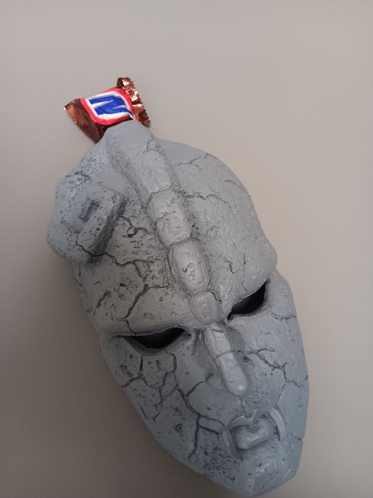 Stone Mask from Jojo sticking from a fun sized snickers bar.