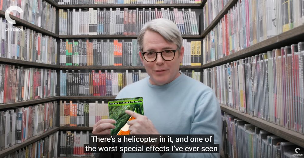 Matthew Broderick of Inspector Gadget fame in the Criterion closet. He's wearing black horn-rimmed glasses and a powder blue sweater (fit of the fall?). He's also holding a standard definition DVD of Godzilla (1998) in his hands. 
The caption reads, "There's a helicopter in it, and one of the worst special effects I've ever seen"