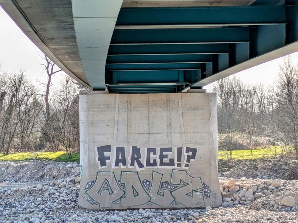 Graffiti avec l'inscription Farce ? en noir sur un pilier de pont avec une partie du pont