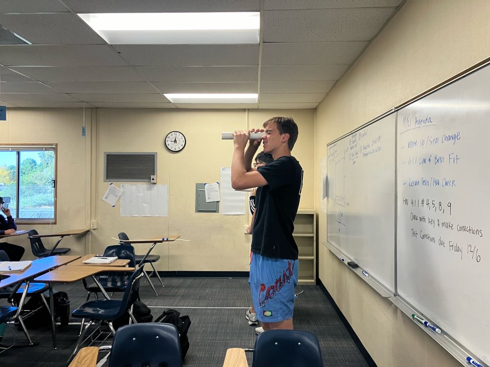 Student holding a pipe looking through it
