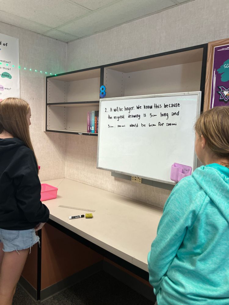 Two students thinking about their answer at the whiteboard
