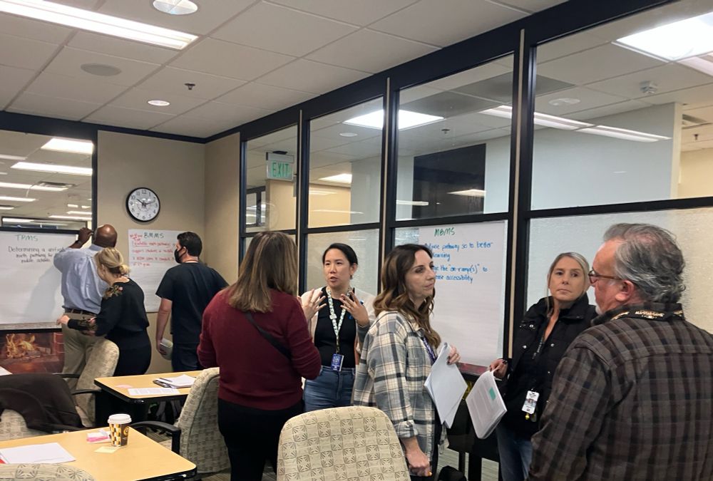 Teachers and administrators in groups of three talking around posters