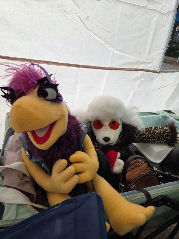 Two puppets sitting next to eachother in a wagon.