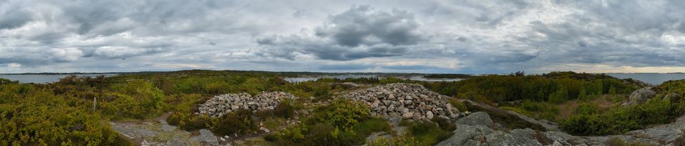 Panoramic view of two cairns in Västra Götaland, Sweden. One can see the shelteted seashore environment surrounding it.