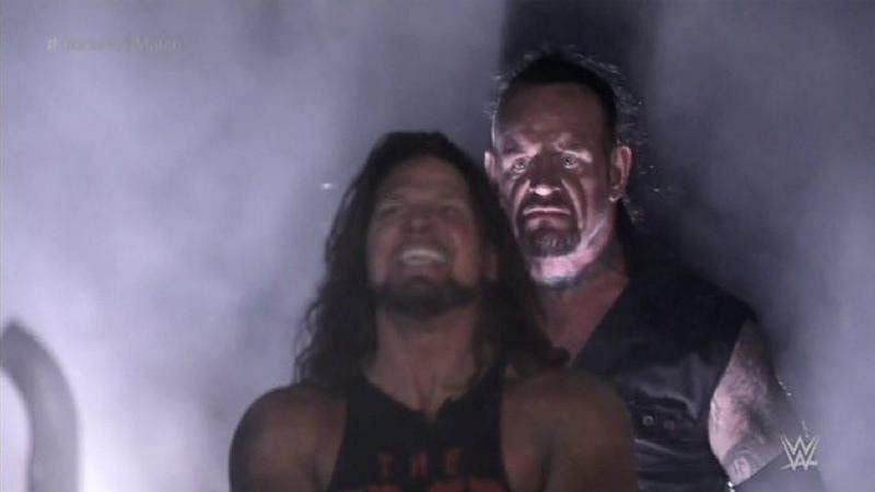 Wrestling meme: Undertaker approaching AJ Styles from behind while Styles celebrates his apparent victory.