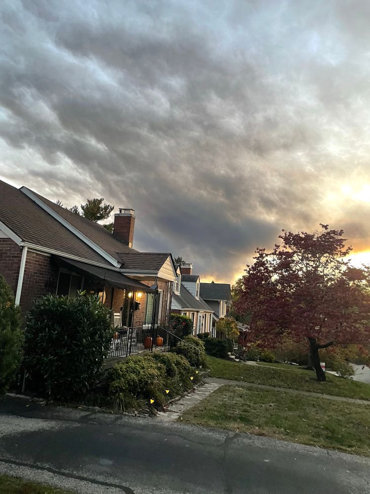 Black clouds of smoke hanging in the sky over suburban houses. 