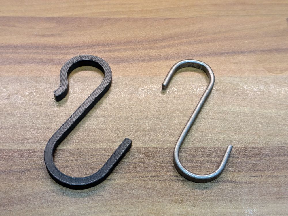 Photo of an asymmetric s-hook in printed plastic, next to a metal one