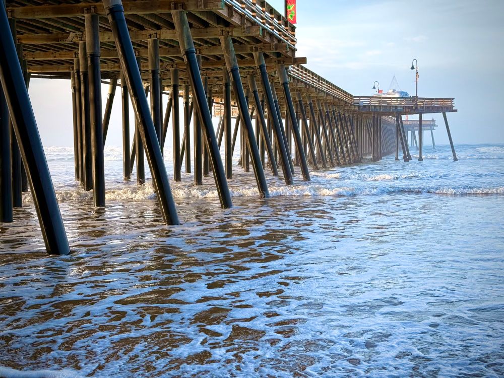 The Pismo beach pier, warmly lit, but shrouded in a light mist. 
