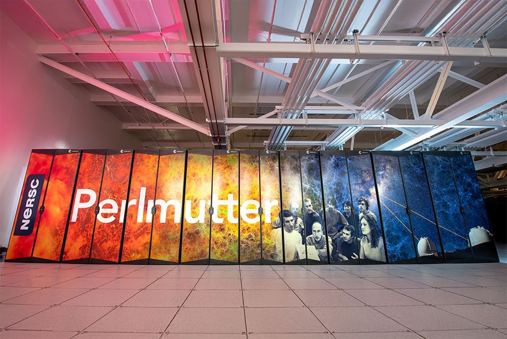 The Perlmutter supercomputer at NERSC features colorful panels with vibrant cosmic imagery, and the name “Perlmutter” is prominently displayed. The panels include images of scientific research and collaboration set against a backdrop of stars and galaxies.