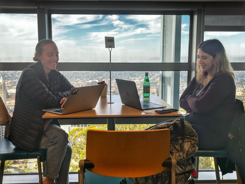 Two women engaged in conversation at a table during a collaborative computing event at Berkeley Lab. 