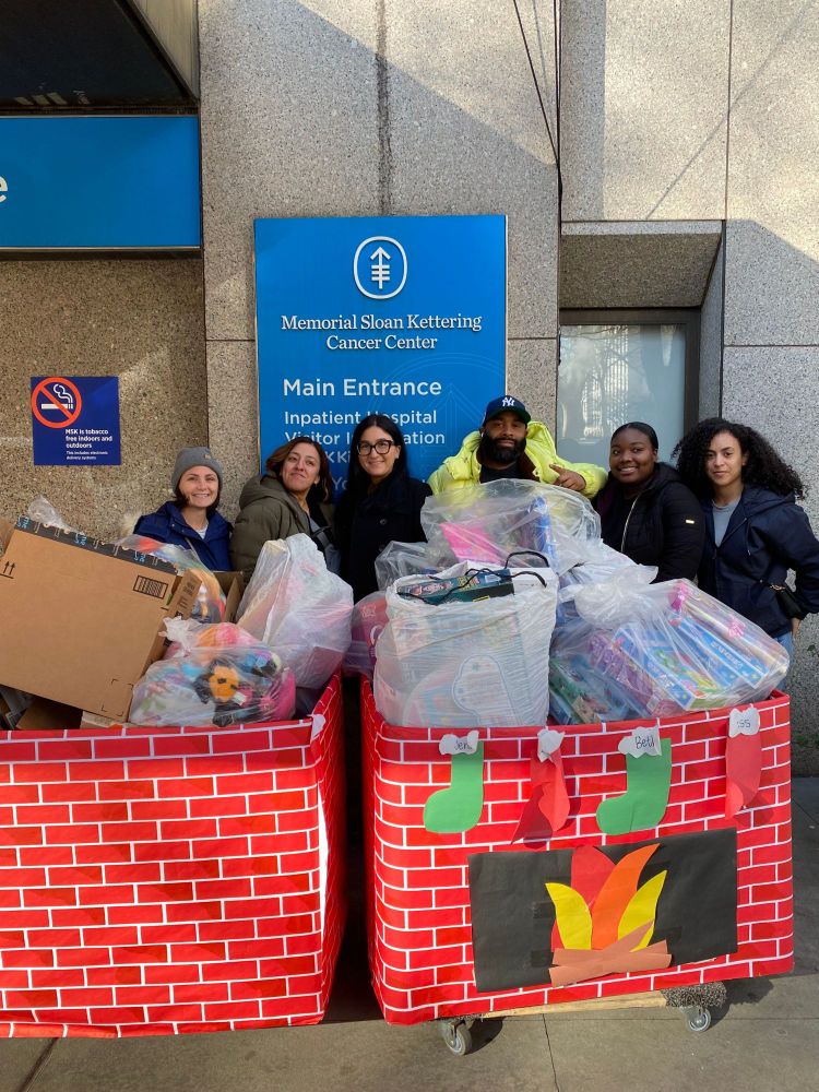 Image of six Kingsborough Community College students behind two huge boxes filled with toys to donate to children at Memorial Sloan Kettering.