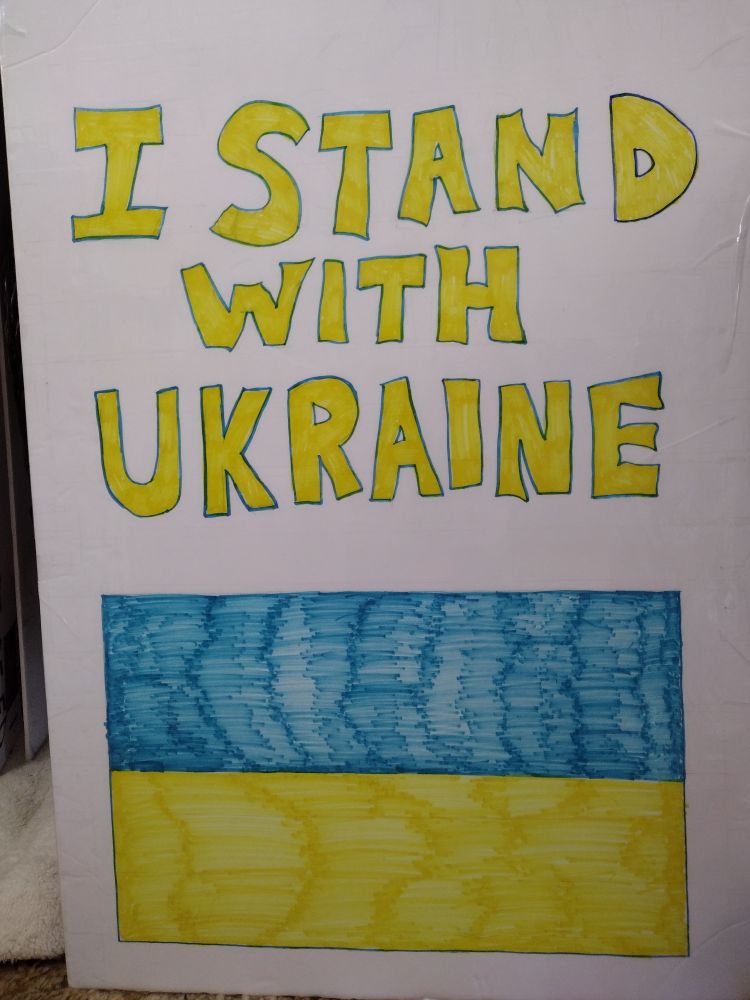 Sign that reads "I stand with Ukraine", with the Ukraine flag below.