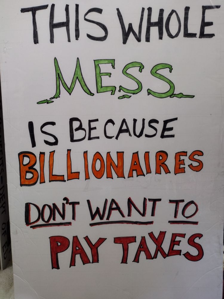Sign that reads "This whole mess is because billionaires don't want to pay taxes."