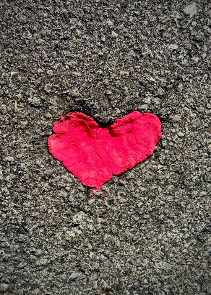 Photo of red clay in heart shaped whole in pavement