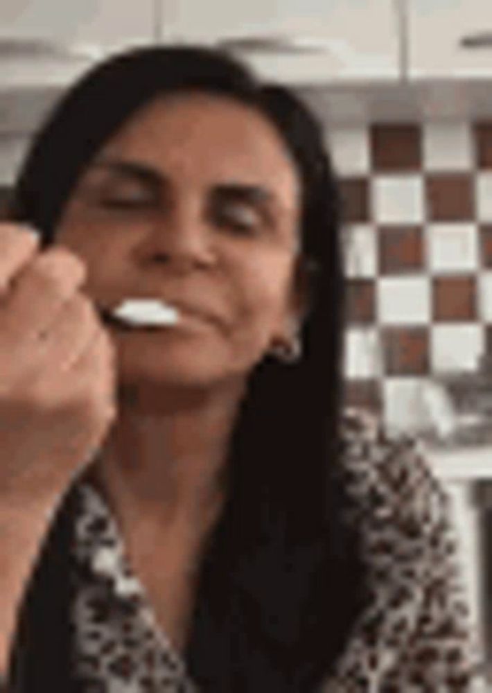 a woman is holding a spoon in her mouth .