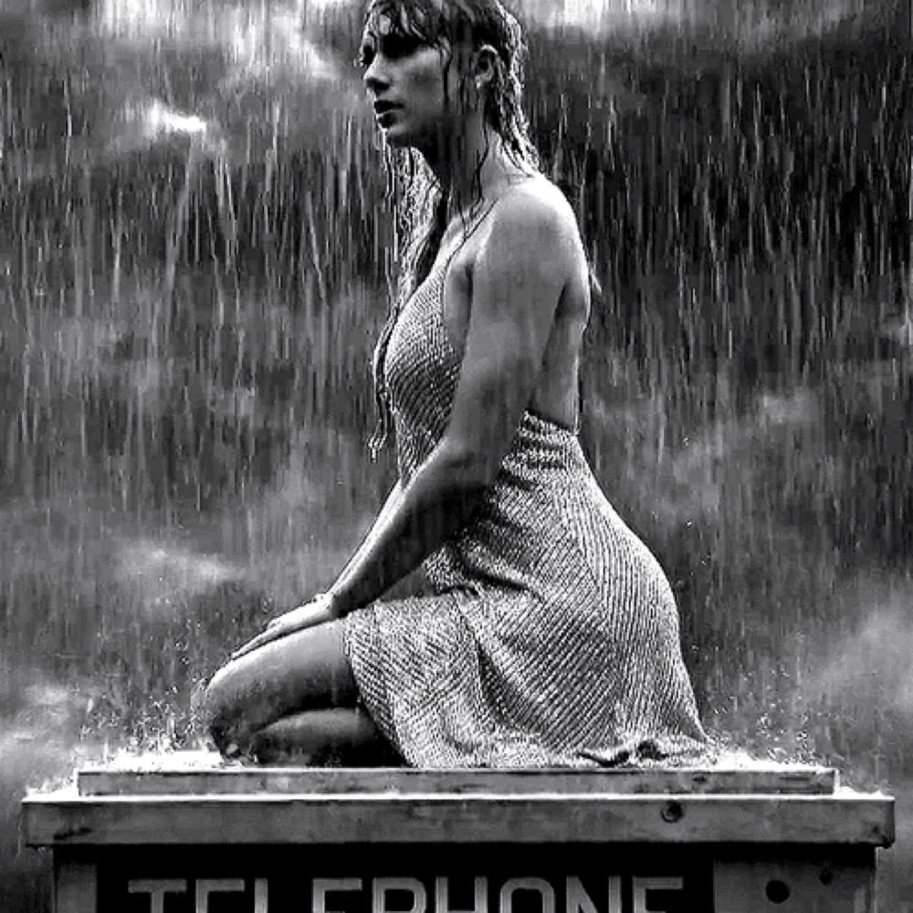 a woman in a dress is sitting on a telephone booth in the rain