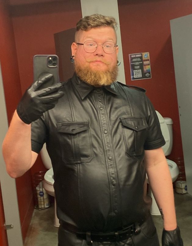 Nerdy and awkward leather boy posing in a bathroom for reassurance 
