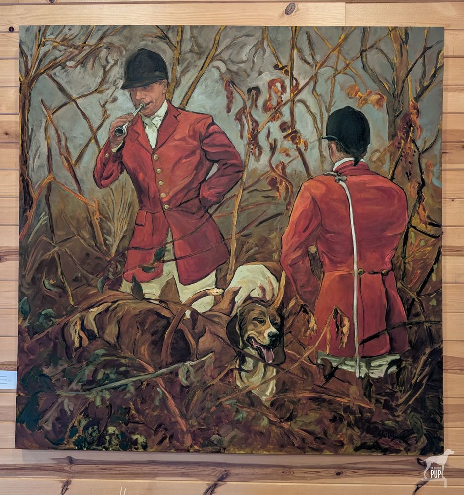 Painting of two huntsman in red coats and black riding caps standing in the field. The man at left is blowing a horn to end the hunt. A foxhound with its tongue out stands between them. 