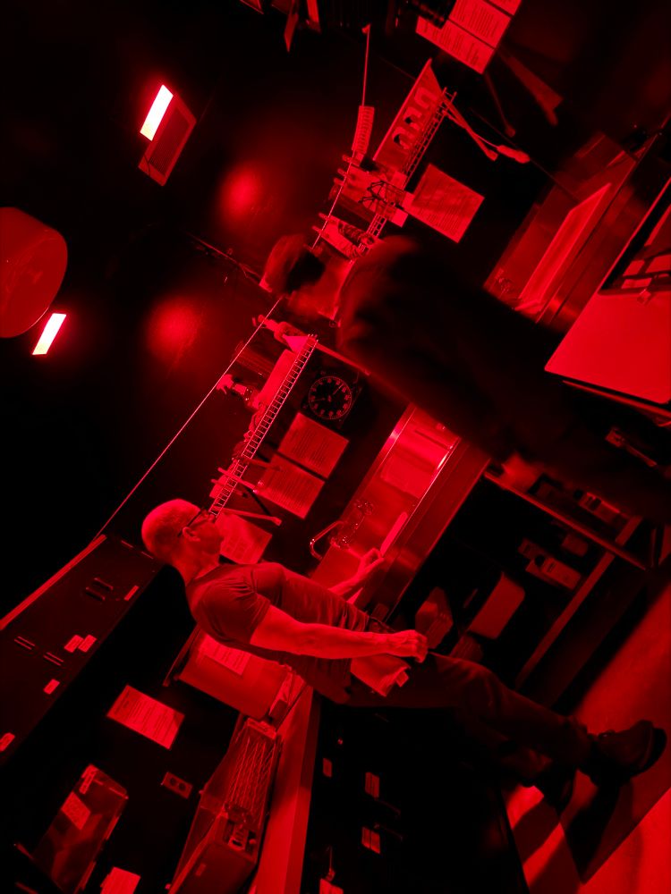 Photo of the darkroom. Processing underway with the red lights on. (photos were already in the fixer so no problem with pulling out the phone to take this shot). 