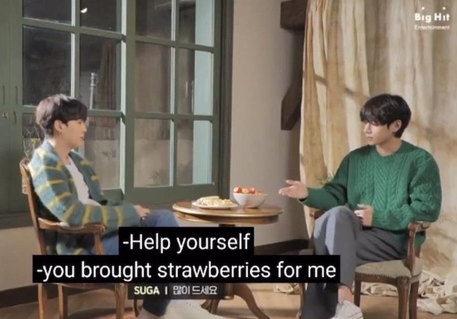 Taegi sitting on chairs & facing each other. Between them there's a table with a plate with peeled clementines and a bowl of strawberries. Tae has his hand open, pointing towards the bowl of strawberries. Caption : (yoongi) Help yourself. (tae) -you brought strawberries for me