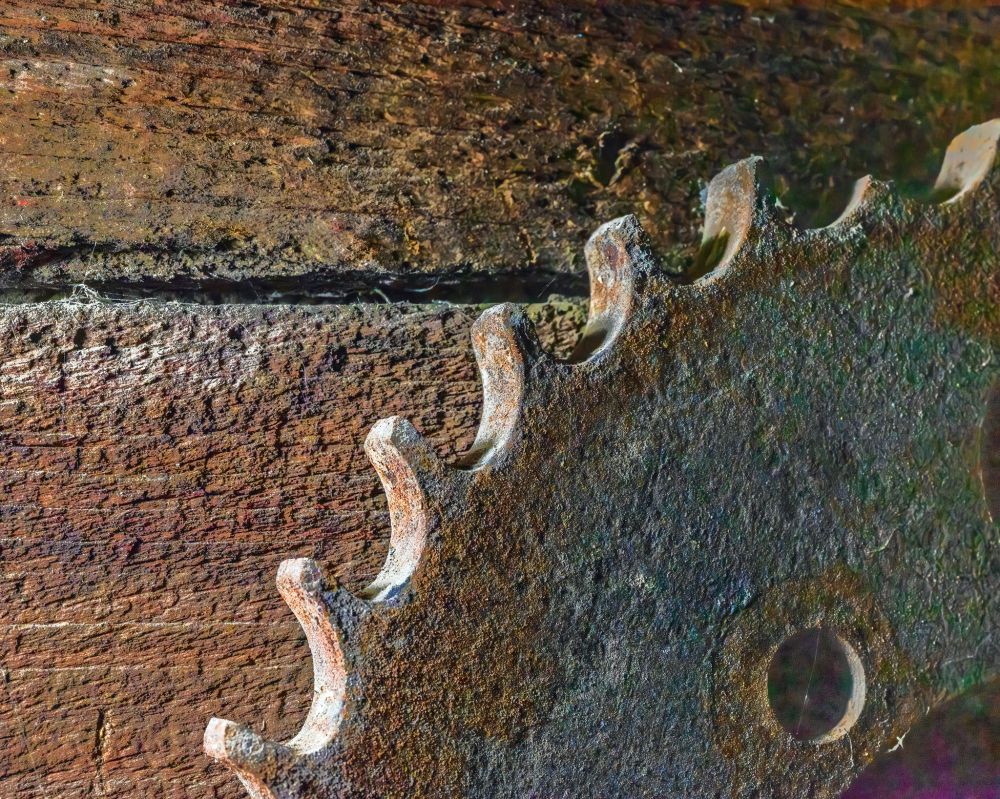 A rusted ragegd gear on an unpainted wooden wall.