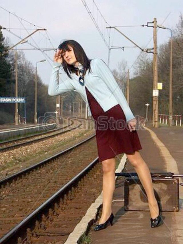 Woman looking out down a train track as she awaits her train
