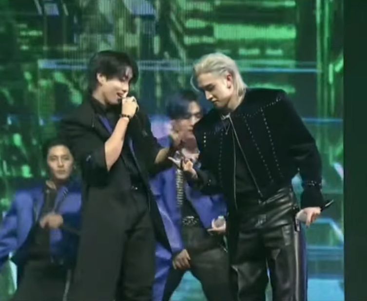 HAN and Bang Chan on stage in black outfits. Chan has a silver mullet.