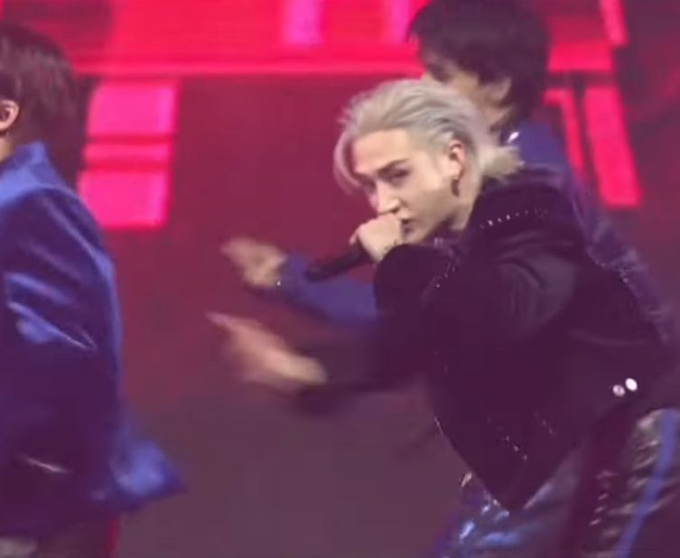 Bang Chan on stage in a black outfit, mic up to his mouth. HE HAS A SILVER MULLET