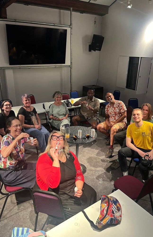 Six (should be seven) mixed deaf and hearing filmgoers holding bottle of air bubbles with Nathon (yellow t-shirt) on the right.