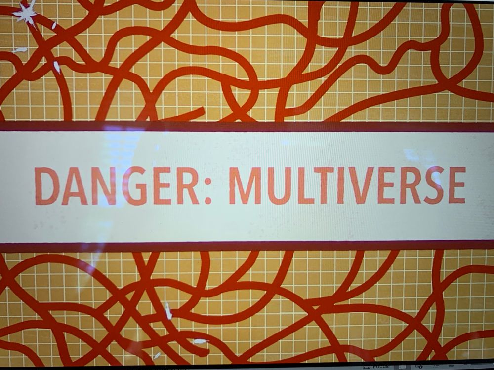 Branching strings in red over a yellow grid in the background, above and below. In the middle is a white bow with an all caps warning: “danger: multiverse.” 