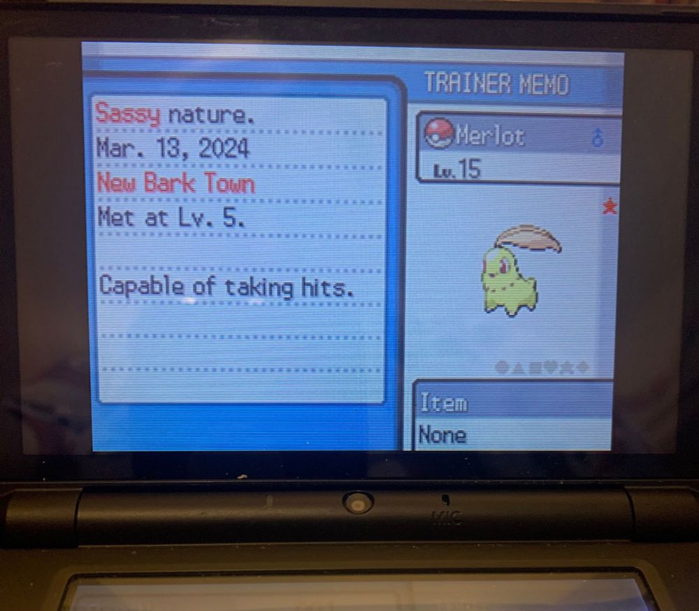 A photo of the pokemon personality screen in HeartGold for my Shiny Chikorita, Merlot. The page says that the Chikorita was met at Level 5 in New Bark Town on March 13th 2024.