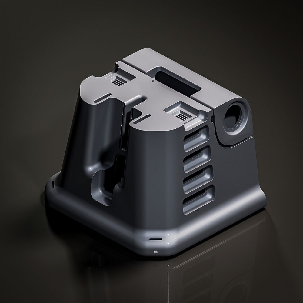A dark gray, industrial-style plastic housing with smooth curves and vents, shaped like a compact tower. It features rounded corners, several layered openings on the sides, and a slot-like recess on top. The surface has a matte finish with subtle highlights, set against a dark reflective background.