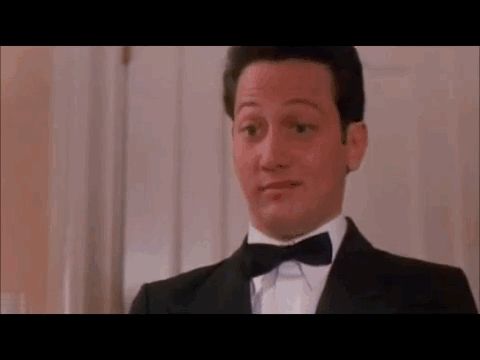 Hotel bellhop rubbing his fingers together, suggesting he wants a tip. 