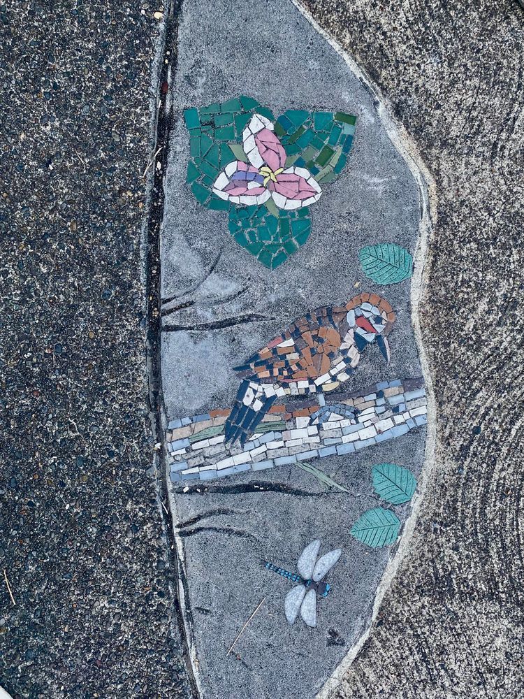 mosaic art of a trillium, dragonfly, and bird inlaid on an offshoot of the Springwater Corridor Trail near Powell Butte