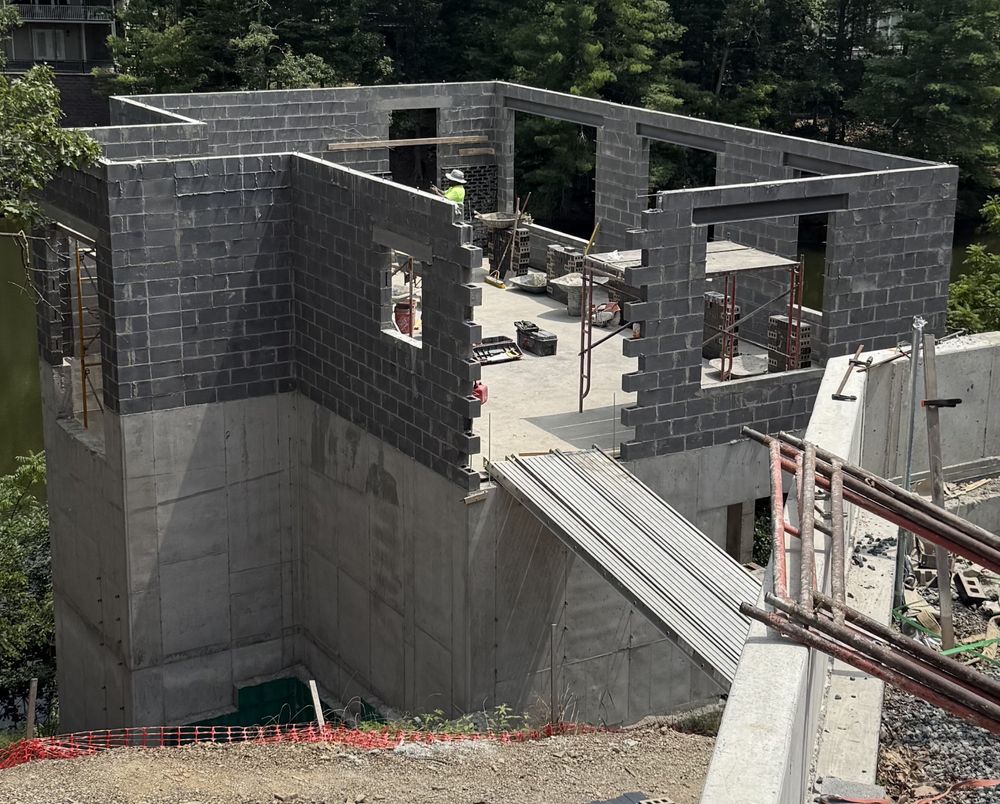 Masons working on a partially completed block wall. The masons are adding black glazed brick to the block wall. They will be bonded together to form a monolithic system.