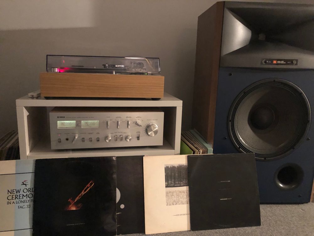 Joy Division and New Order records stacked in front of a big 1970s hifi system 