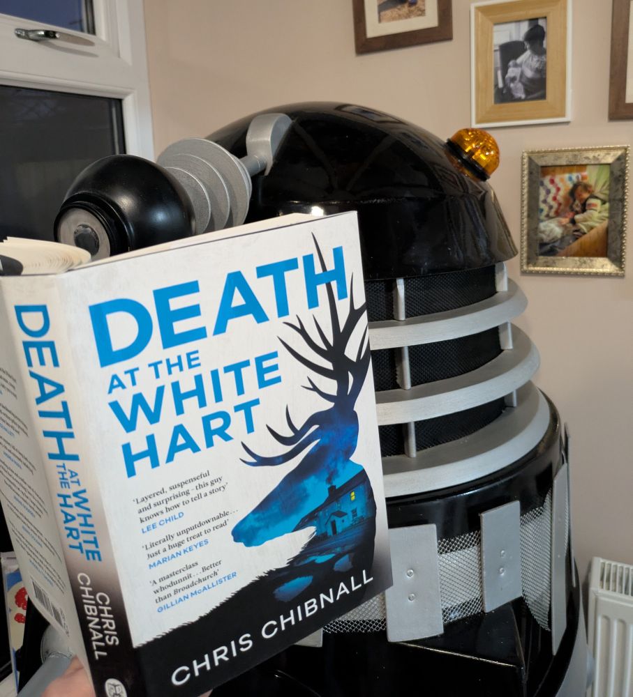 A Dalek reading a book. 