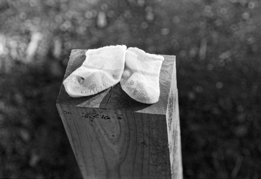 A pair of white Carters booties left atop a post.