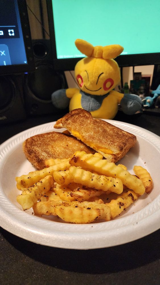 Photo of a grilled cheese sandwich and some lemon pepper fries. Makuhita sits behind the plate. 
