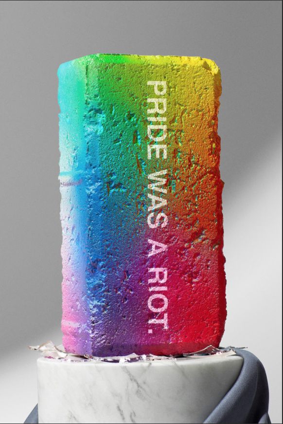 A rainbow-hued brick with PRIDE WAS A RIOT sprayed on the side facing us