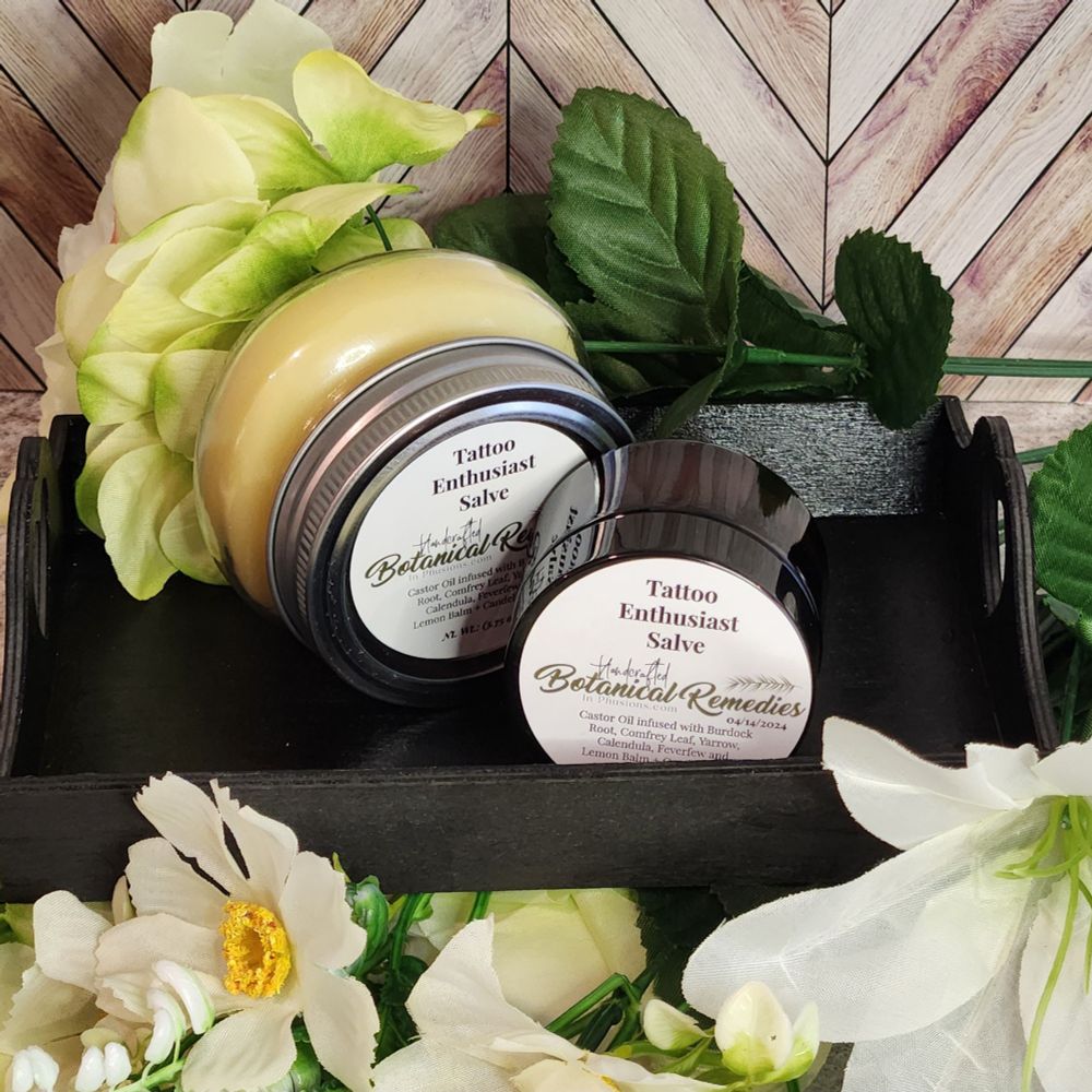 Two different sized jars of body butter placed on a decorative tray surrounded by colorful flowers.