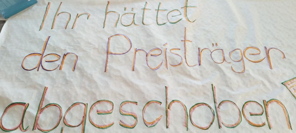 Transpi mit dem Text: "Ihr hättet den Preisträger abgeschoben!"