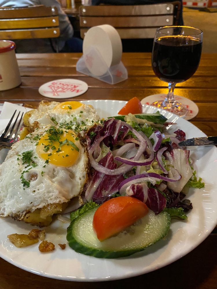 Spiegelei, Salat, Rotwein auf Holztisch