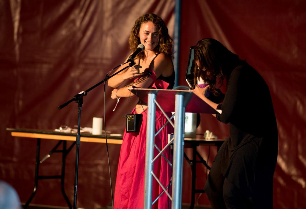 Helen on stage with Phoenix. Helen is grinning and Phoenix is bent over laughing